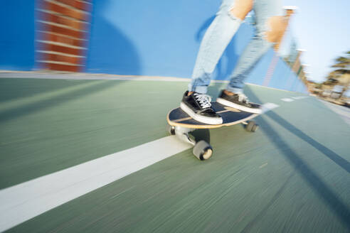 Beine einer Frau, die auf der Straße Skateboard fährt - PGF00034