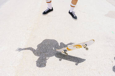 Legs of young woman doing stunt with skateboard on street during sunny day - PGF00054