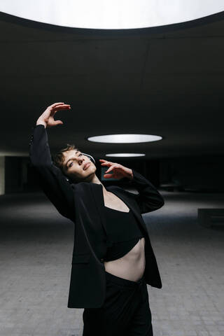 Trans young man listening music and dancing in illuminated basement stock photo