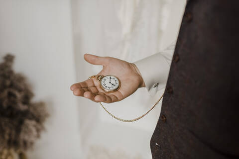 Midsection of bridegroom holding chain watch in hand stock photo