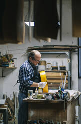 Craftsman making guitar while standing at workshop - DGOF01466