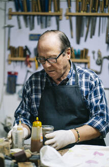 Älterer Mann bei der Arbeit an einer Werkbank in einer Werkstatt - DGOF01471