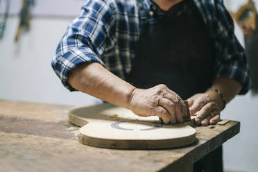 Mann, der in einer Werkstatt stehend die Form einer Gitarre formt - DGOF01479