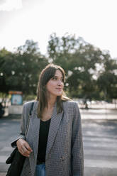 Young woman looking away while standing on street - GRCF00378