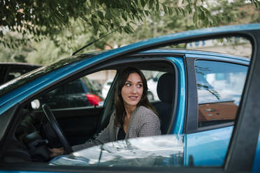 Junge Frau schaut weg, während sie im Auto sitzt - GRCF00382