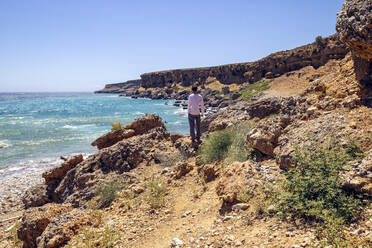 Man admiring view while standing on beach at Plakias, Crete, Greece - MAMF01300