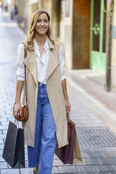 Frau trägt Einkaufstasche beim Gehen auf dem Fußweg in der Stadt - JSMF01717