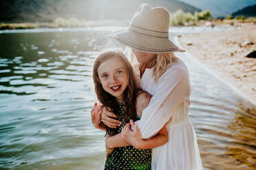 Mom and Daughter hugging and smiling while standing in a lake - CAVF89493