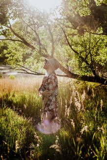 Vertikales Porträt einer jungen Frau, die im Wald steht und wegschaut - CAVF89497