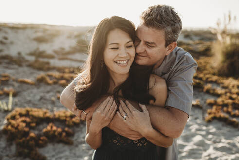 Loving husband with closed eyes embraces beautiful smiling wife - CAVF89563