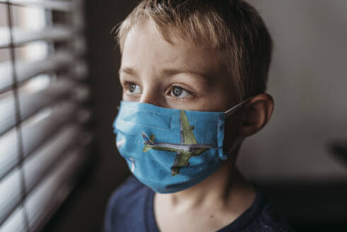Porträt eines Jungen im Schulalter mit Maske bei sich zu Hause - CAVF89611