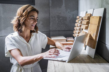 Geschäftsfrau arbeitet am Laptop mit Holzfliesen auf dem Schreibtisch im Büro - DLTSF01224