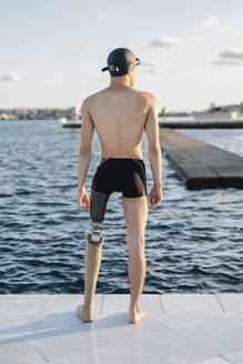 Amputierter Mann schaut auf das Meer, während er an einem sonnigen Tag auf der Promenade steht - JCZF00245