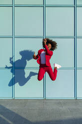 Woman enjoying while jumping against wall - MGIF01001