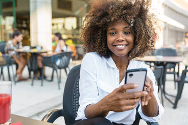 Woman text messaging on smart phone while sitting at cafe - MGIF01011