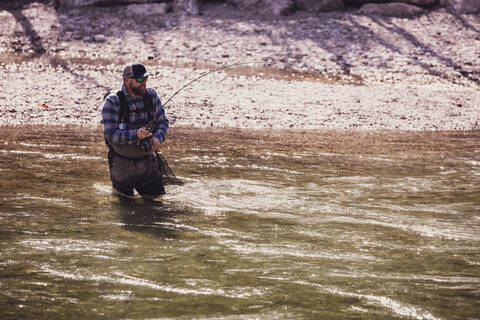 Fly fisherman catching fish from river on sunny day stock photo