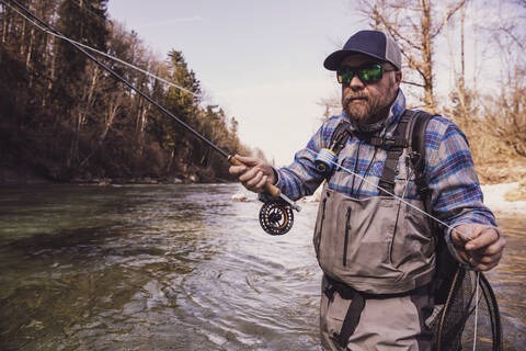 Mann fängt an einem sonnigen Tag Fische aus dem Fluss, lizenzfreies Stockfoto
