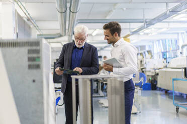 Senior manager discussing machine part with engineer at factory - MOEF03289