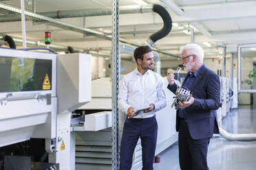 Ein leitender Angestellter bespricht ein Maschinenteil mit einem Ingenieur an einer Maschine in einer Fabrik - MOEF03307