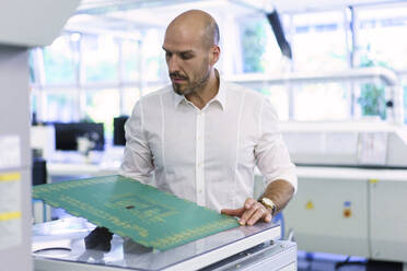 Confident mature male technician examining large circuit board at factory - MOEF03375