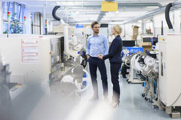 Geschäftsfrau und Geschäftsmann diskutieren über Maschinen in der Beleuchtungsindustrie - MOEF03427