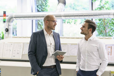 Male professionals discussing while looking at each other in factory - MOEF03444