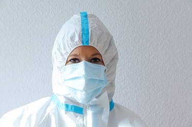 Nurse wearing protective suit and workwear while standing against  - PGF00093