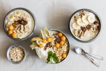 Three bowls of porridge with oats, flax seed, winter cherries and bananas - EVGF03760