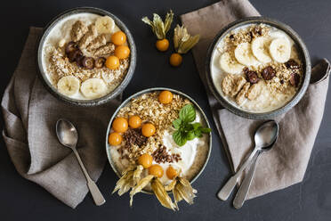 Three bowls of porridge with oats, flax seed, winter cherries and bananas - EVGF03768