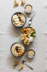 Three bowls of porridge with oats, flax seed, winter cherries and bananas - EVGF03773