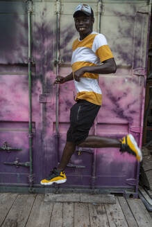 Young man walking against purple container - NGF00665