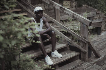 Junger Mann, der auf einer Treppe sitzend Musik hört - NGF00674