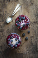 Garnished blueberry buckwheat porridge cups kept by spoon on table - EVGF03777