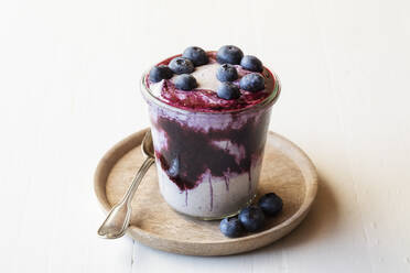Cup of blueberry buckwheat porridge garnished with blueberry kept on plate - EVGF03778