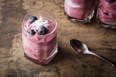 Red blueberry whipped cream kept with spoon on table - EVGF03789