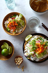 Gesundes Mittagessen mit veganem Reisnudelsalat mit frischem Gemüse, Limetten- und Erdnusssauce und einem Glas Wasser - ADSF15778