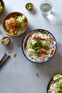 Gesundes Mittagessen mit veganem Reisnudelsalat mit frischem Gemüse, Limetten- und Erdnusssauce und einem Glas Wasser - ADSF15787