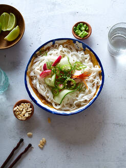 Gesundes Mittagessen mit veganem Reisnudelsalat mit frischem Gemüse, Limetten- und Erdnusssauce und einem Glas Wasser - ADSF15789