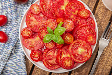 Tomatensalat und Basilikumblätter auf einem Teller, Ansicht von oben - ADSF15800