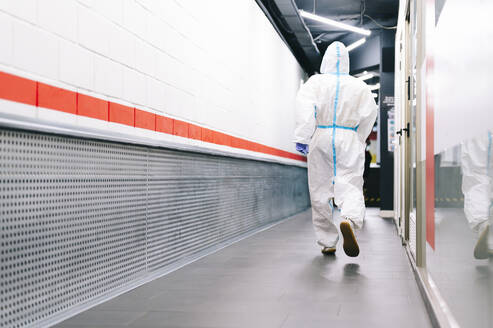 Healthcare man walking while wearing protective suit in hospital - PGF00109