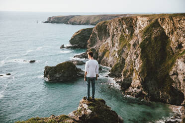 Mann steht am Rande einer Klippe über dem malerischen Meer, Bedruthan Steps, Cornwall, UK - FSIF05175