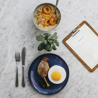 Apricot porridge and confit duck leg and egg on restaurant table - FSIF05180