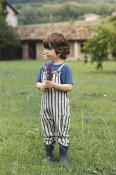 Junge schaut weg, während er im Gras auf einer Wiese steht - ALBF01563