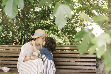Sohn küsst seine Mutter auf einer Bank im Hinterhof sitzend - ALBF01583