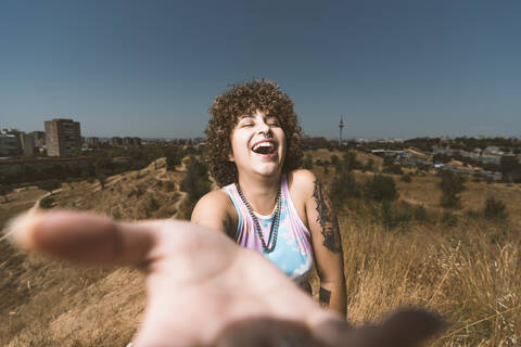 Lächelnde Frau zeigt ihre Hand, während sie vor einem klaren Himmel steht, lizenzfreies Stockfoto