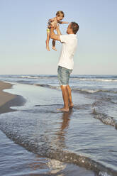 Man picking up son while standing at beach - VEGF02944