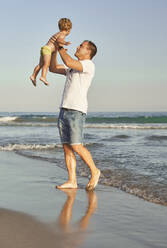 Man picking up while walking at beach - VEGF02945