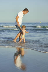 Vater und Sohn spielen zusammen im Wasser am Strand - VEGF02946