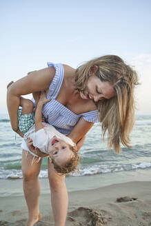 Mother playing with son while standing at beach - VEGF02956