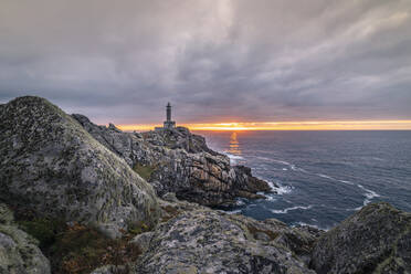 Spektakuläre Kulisse von Leuchtturm auf rauen Klippen in der Nähe von Meer auf dem Hintergrund der Sonnenuntergang Himmel - ADSF15834